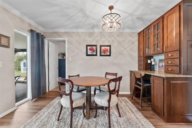 dining space with wood-type flooring, crown molding, and an inviting chandelier