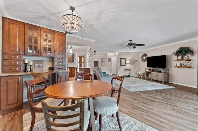 dining space with a textured ceiling, ceiling fan with notable chandelier, light hardwood / wood-style flooring, and ornamental molding