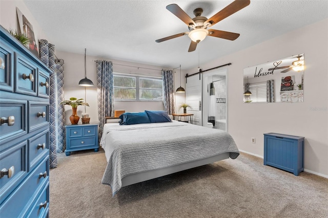 carpeted bedroom with a barn door, ceiling fan, and a textured ceiling