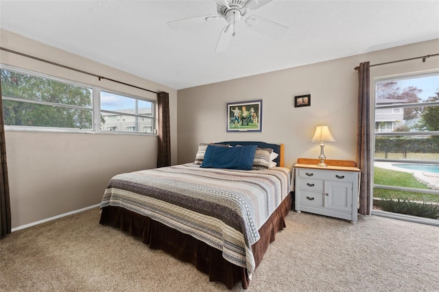 bedroom with multiple windows, ceiling fan, and light colored carpet