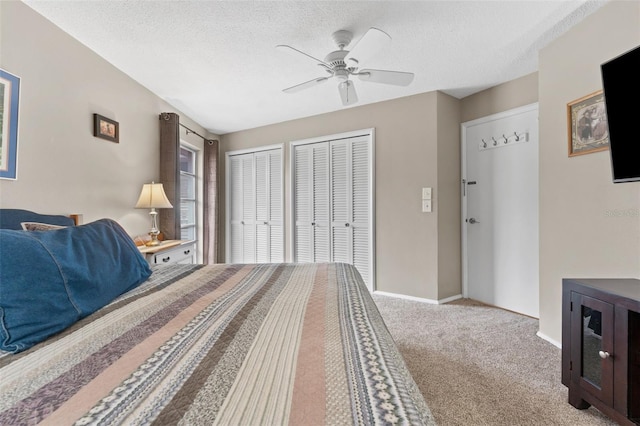 carpeted bedroom featuring a textured ceiling, two closets, and ceiling fan