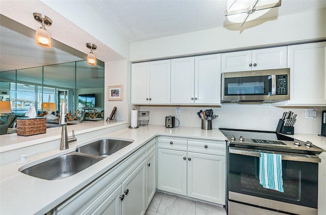 kitchen featuring decorative light fixtures, kitchen peninsula, sink, stainless steel appliances, and white cabinets