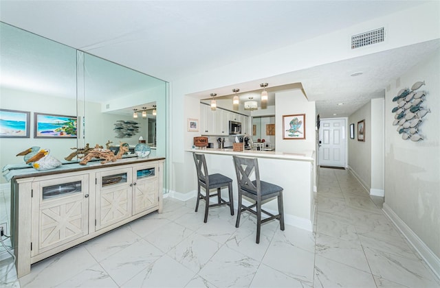 kitchen with white cabinetry, kitchen peninsula, and a breakfast bar area