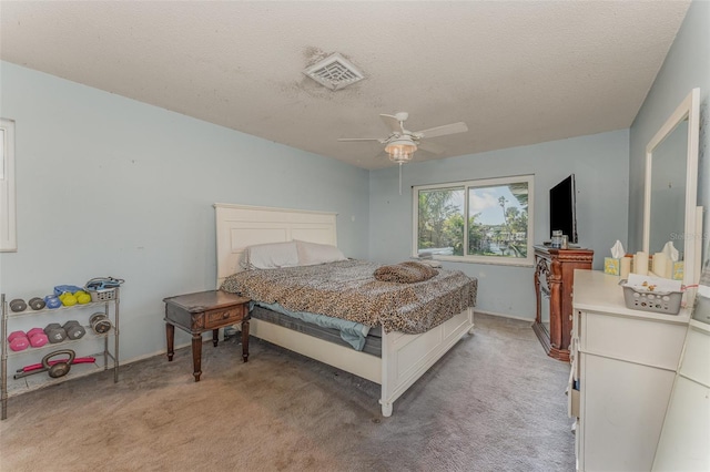 bedroom featuring light carpet, a textured ceiling, and ceiling fan