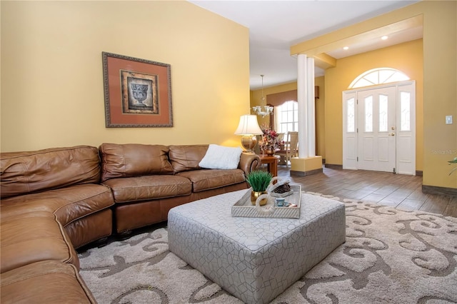 living room featuring ornate columns, hardwood / wood-style floors, and a chandelier