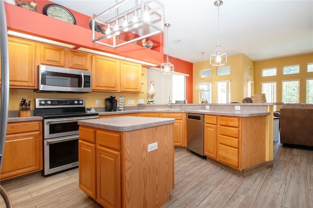 kitchen with a kitchen island, sink, hanging light fixtures, and appliances with stainless steel finishes