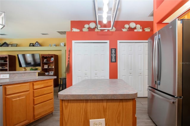 kitchen featuring stainless steel fridge, a center island, and wood-type flooring