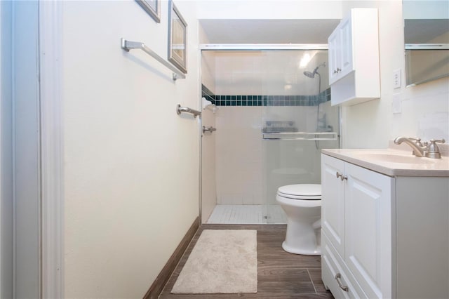 bathroom with hardwood / wood-style flooring, vanity, toilet, and a shower with shower door