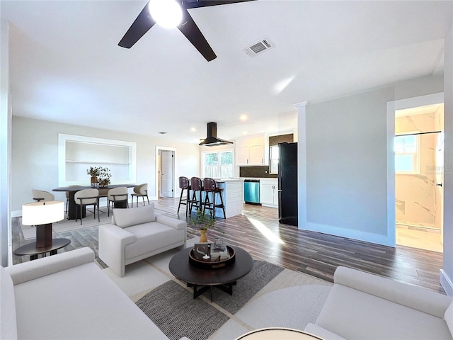 living room featuring hardwood / wood-style floors, built in shelves, and ceiling fan