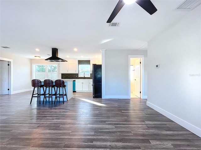 kitchen with white cabinets, dark hardwood / wood-style floors, black refrigerator, and ceiling fan