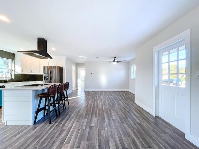 kitchen featuring white cabinets, decorative backsplash, stainless steel fridge, ceiling fan, and island exhaust hood