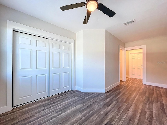 unfurnished bedroom with ceiling fan, dark hardwood / wood-style floors, and a closet