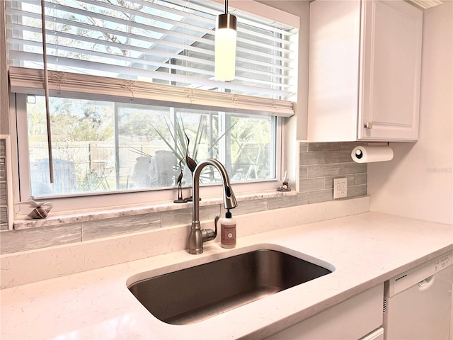 kitchen with light stone countertops, dishwasher, sink, decorative backsplash, and white cabinets