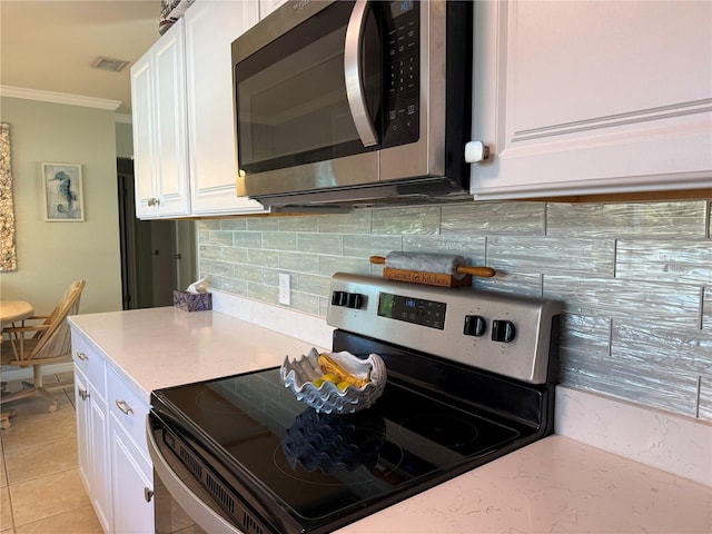 kitchen with white cabinets, appliances with stainless steel finishes, light tile patterned floors, and crown molding