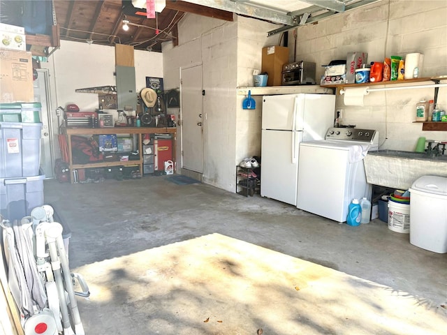 garage featuring independent washer and dryer, white refrigerator, and sink