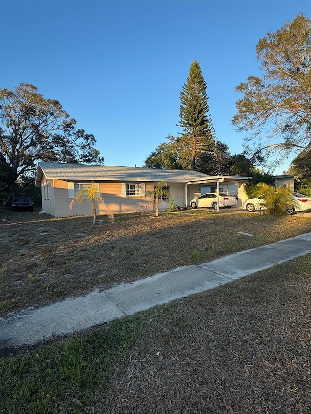 ranch-style house featuring a front lawn and a carport