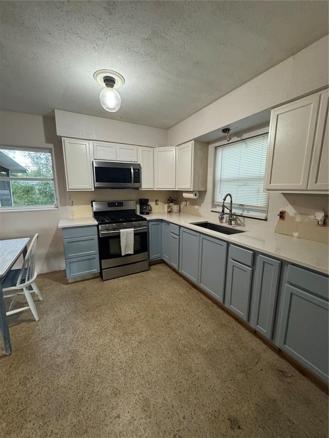 kitchen with sink, a textured ceiling, appliances with stainless steel finishes, and gray cabinetry