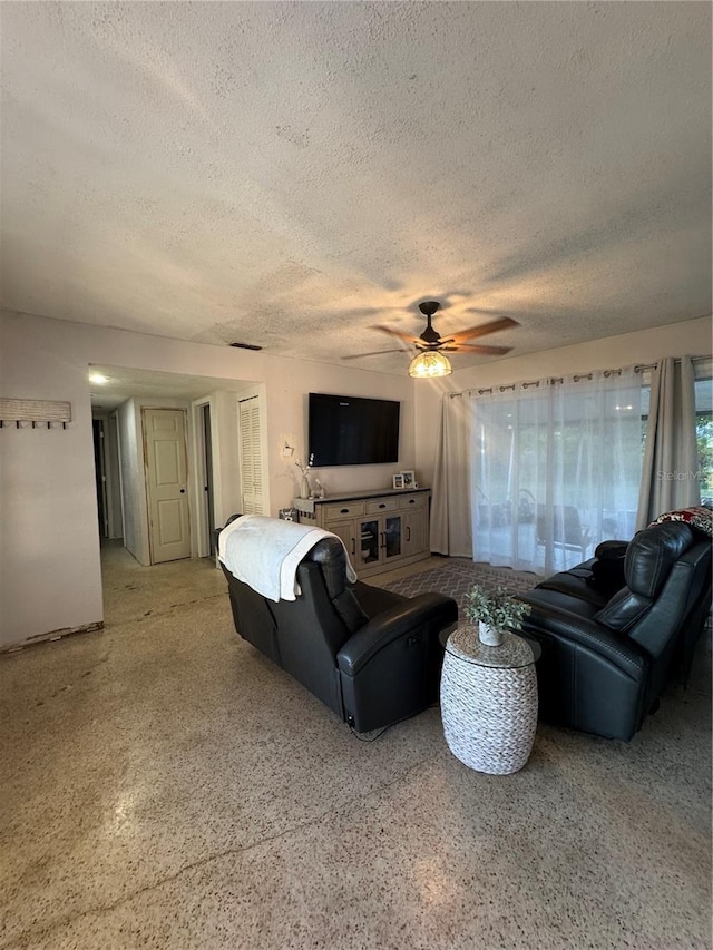 living room featuring ceiling fan and a textured ceiling