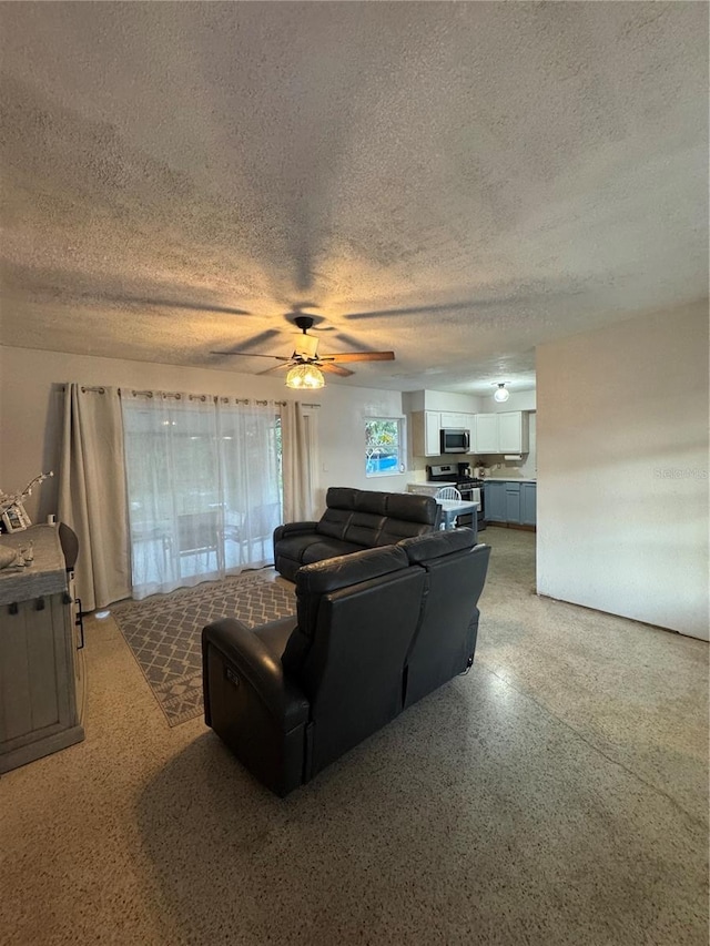 living room featuring ceiling fan and a textured ceiling