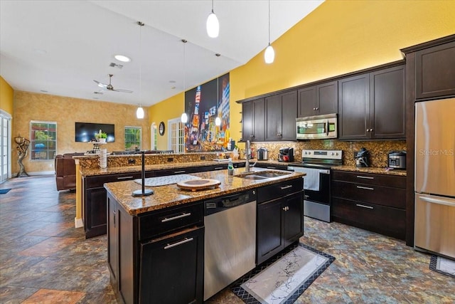 kitchen with ceiling fan, decorative light fixtures, a kitchen island with sink, dark brown cabinets, and appliances with stainless steel finishes