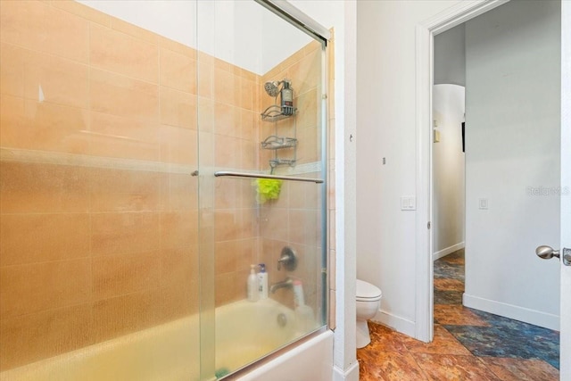 bathroom featuring toilet and shower / bath combination with glass door