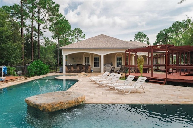 view of swimming pool with a deck, a pergola, an outdoor bar, pool water feature, and a patio area