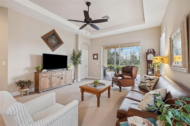 living room featuring ceiling fan, light carpet, and a tray ceiling