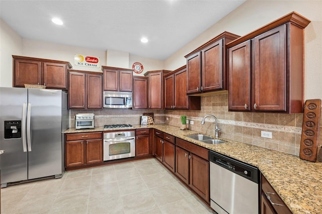 kitchen with sink, light stone counters, decorative backsplash, light tile patterned floors, and appliances with stainless steel finishes