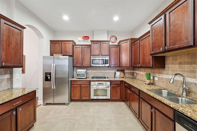 kitchen with decorative backsplash, sink, light stone counters, and stainless steel appliances