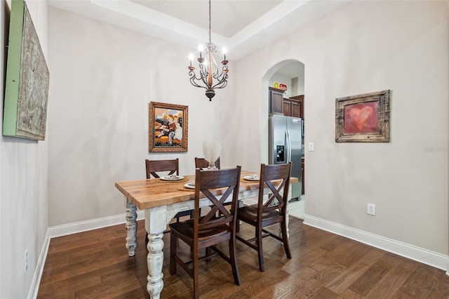 dining space featuring a chandelier, dark hardwood / wood-style flooring, and a tray ceiling