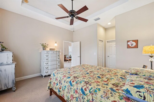 carpeted bedroom featuring a raised ceiling and ceiling fan