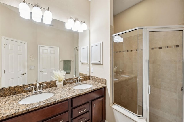 bathroom featuring a shower with door and vanity