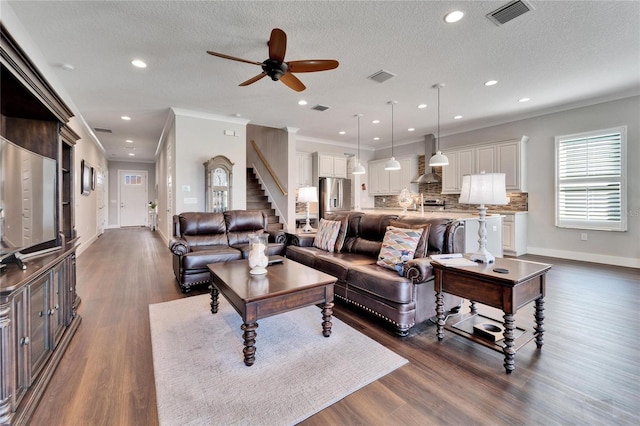 living room with ornamental molding, dark hardwood / wood-style flooring, a textured ceiling, and ceiling fan