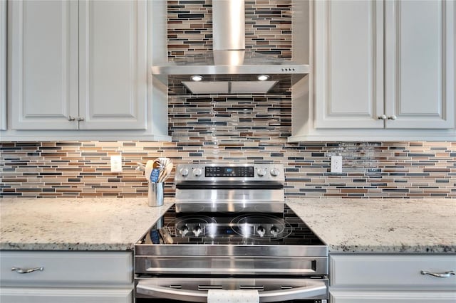 kitchen with light stone countertops, extractor fan, stainless steel electric stove, backsplash, and white cabinetry