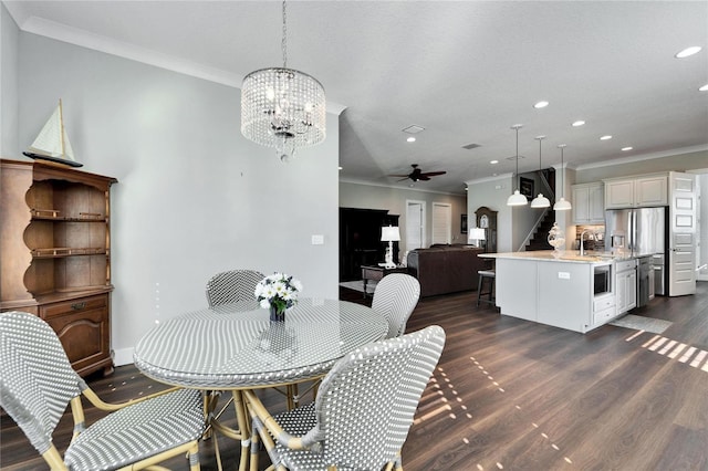 dining space with ceiling fan with notable chandelier, dark hardwood / wood-style flooring, sink, and crown molding