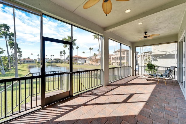 unfurnished sunroom with ceiling fan and a water view