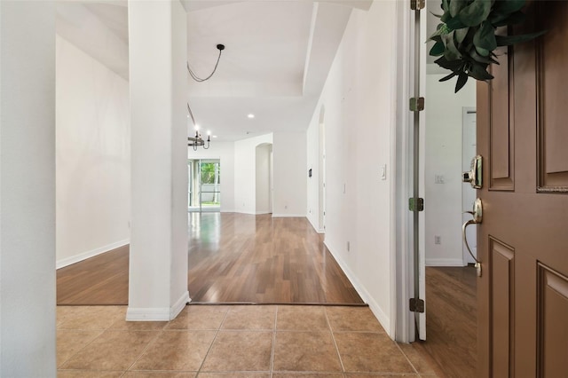 hallway featuring light tile patterned floors and an inviting chandelier