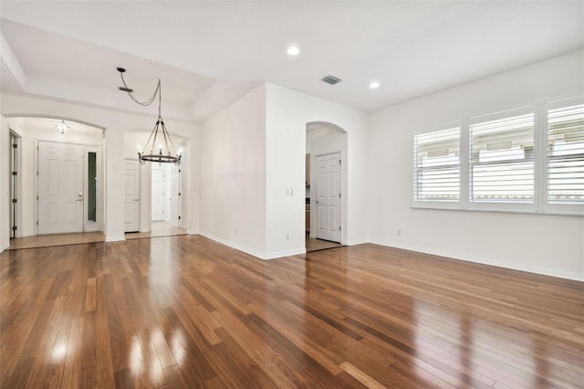 unfurnished living room with wood-type flooring and a chandelier