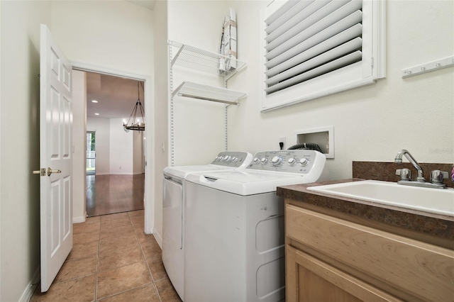 clothes washing area with sink, light tile patterned flooring, washer and dryer, and an inviting chandelier