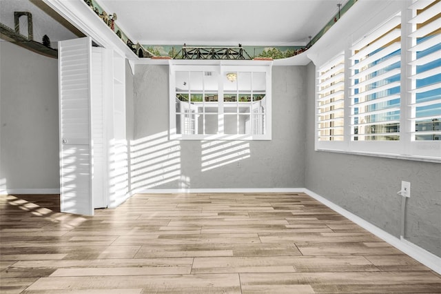 spare room featuring baseboards and wood finished floors