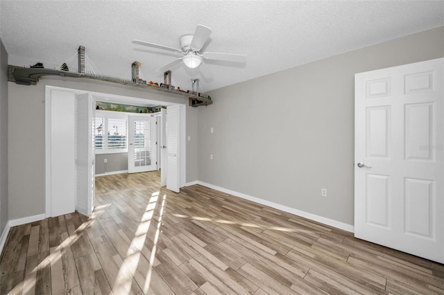 unfurnished bedroom featuring light wood-style flooring, baseboards, and a textured ceiling