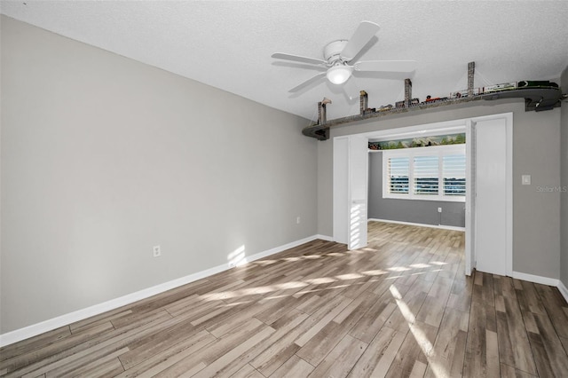 unfurnished room with a textured ceiling, wood finished floors, a ceiling fan, and baseboards