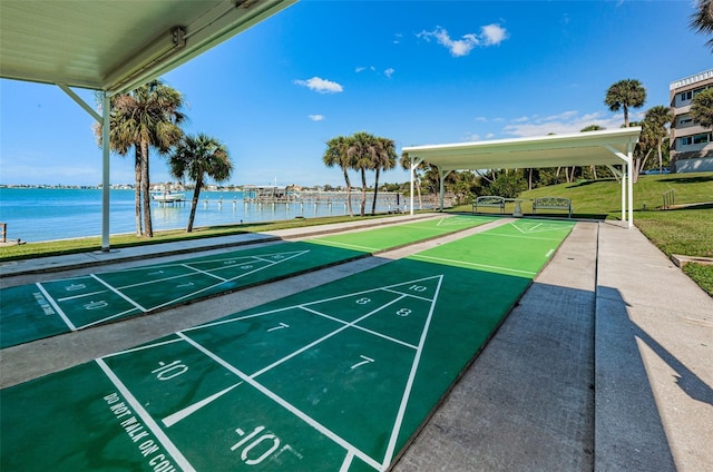 view of property's community with a water view, a yard, and shuffleboard