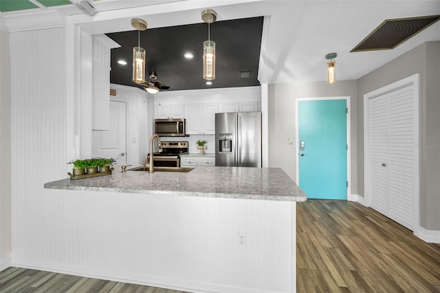 kitchen featuring visible vents, white cabinets, appliances with stainless steel finishes, wood finished floors, and a peninsula