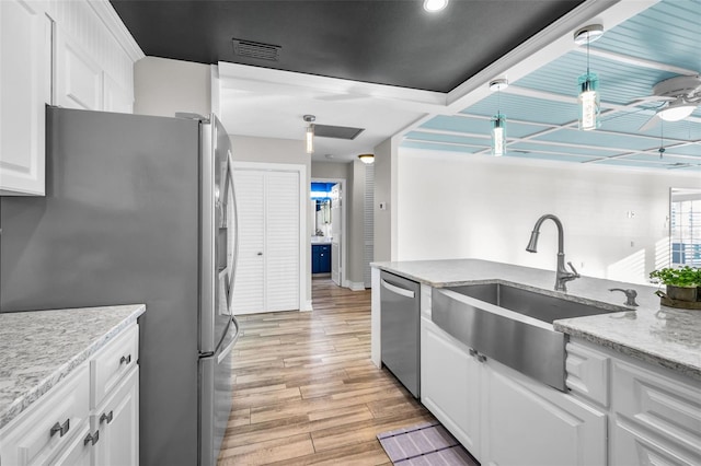 kitchen with white cabinets, a ceiling fan, stainless steel appliances, light wood-style floors, and a sink