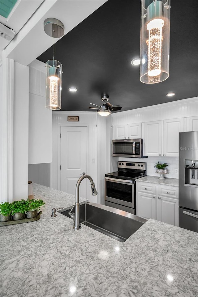 kitchen with ceiling fan, stainless steel appliances, a sink, white cabinetry, and pendant lighting