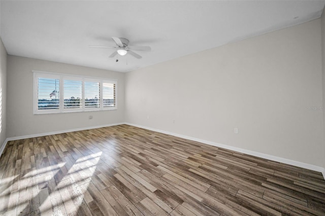 empty room featuring ceiling fan, wood finished floors, and baseboards