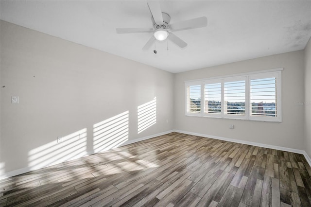 spare room featuring wood finished floors, a ceiling fan, and baseboards