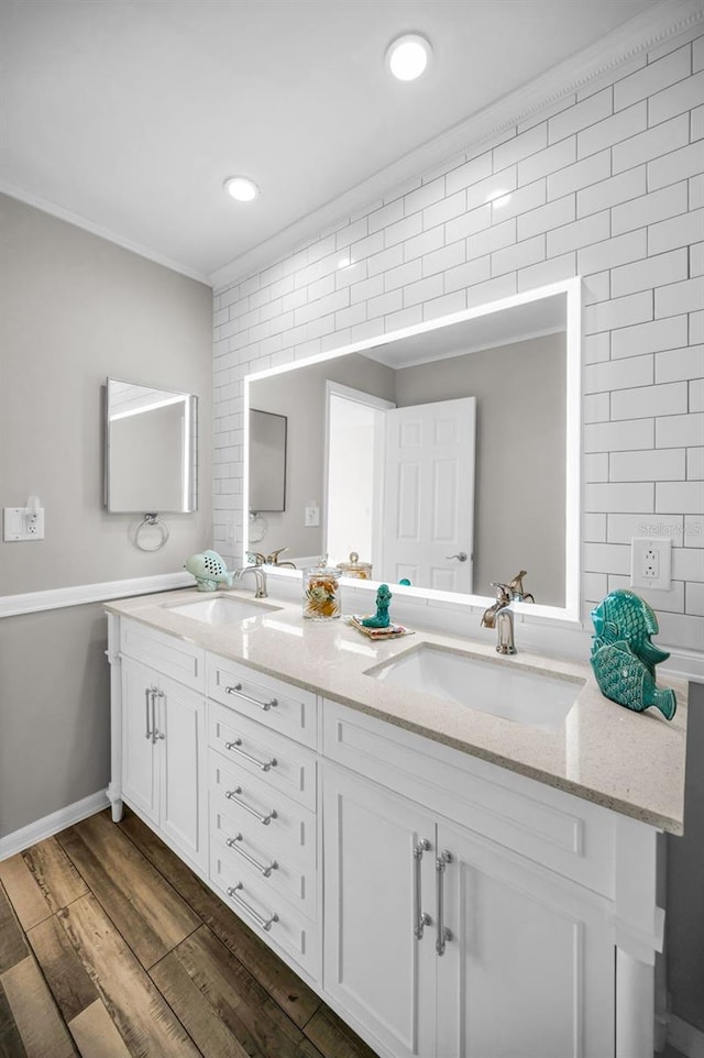 full bath with crown molding, double vanity, a sink, and wood finished floors