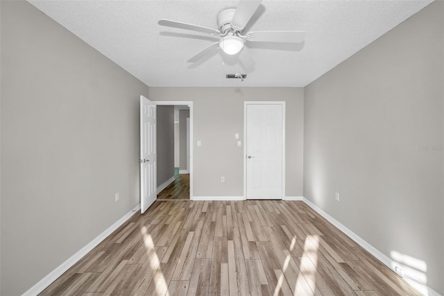 unfurnished bedroom featuring a textured ceiling, baseboards, and wood finished floors